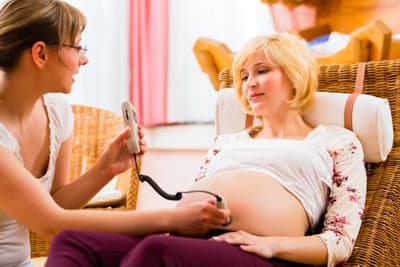 Hebammen begleiten Mütter vor, während und nach der Geburt Hebamme überprüft die Herztöne eines Babys im Mutterleib